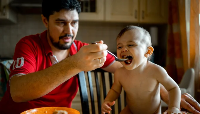 father feeding toddler